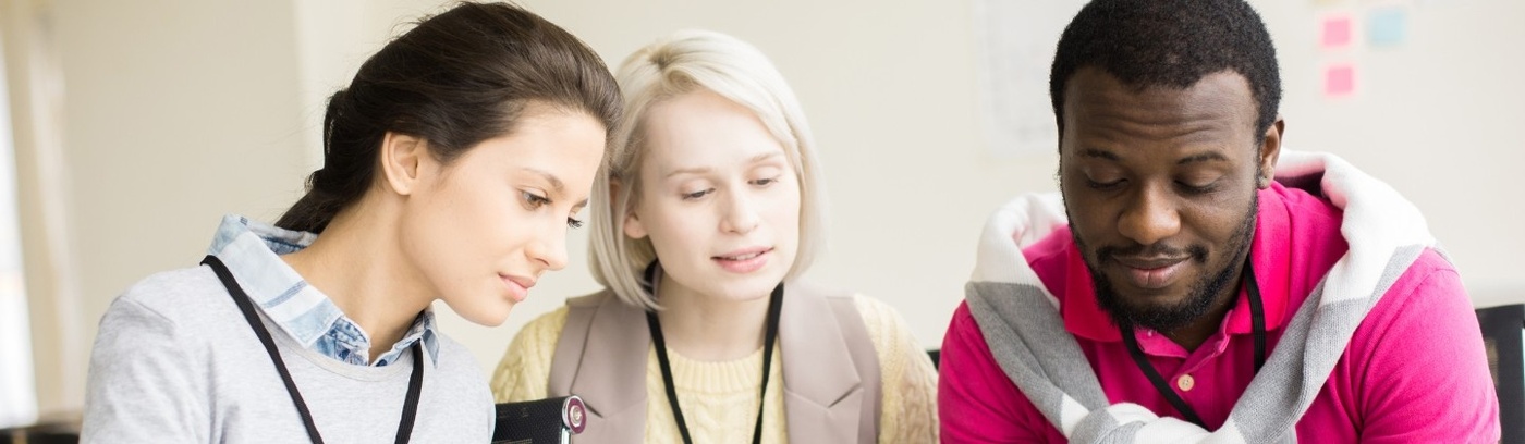 A group of three focuses on paperwork, with one member using a pen, suggesting a brainstorming or planning session