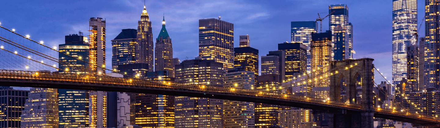 The New York City skyline at dusk, with twinkling lights and a gradient sky transitioning from orange to deep blue.