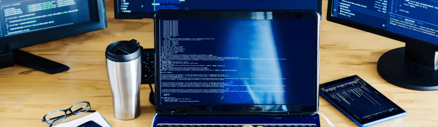 A person engaged in typing on a laptop, supported by two side monitors for enhanced productivity.