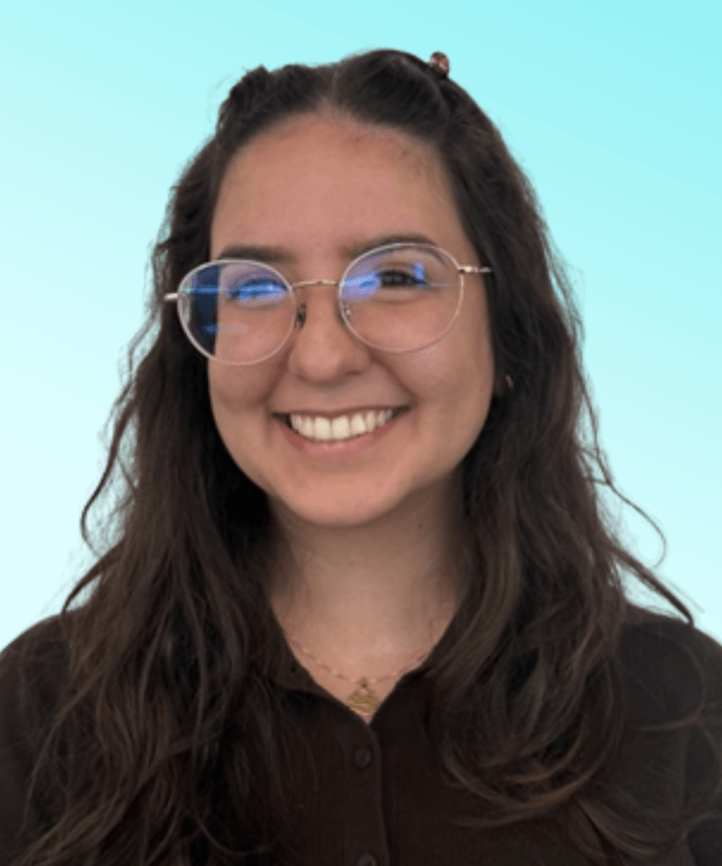 Woman with round glasses and dark brunette hair in front of blue background