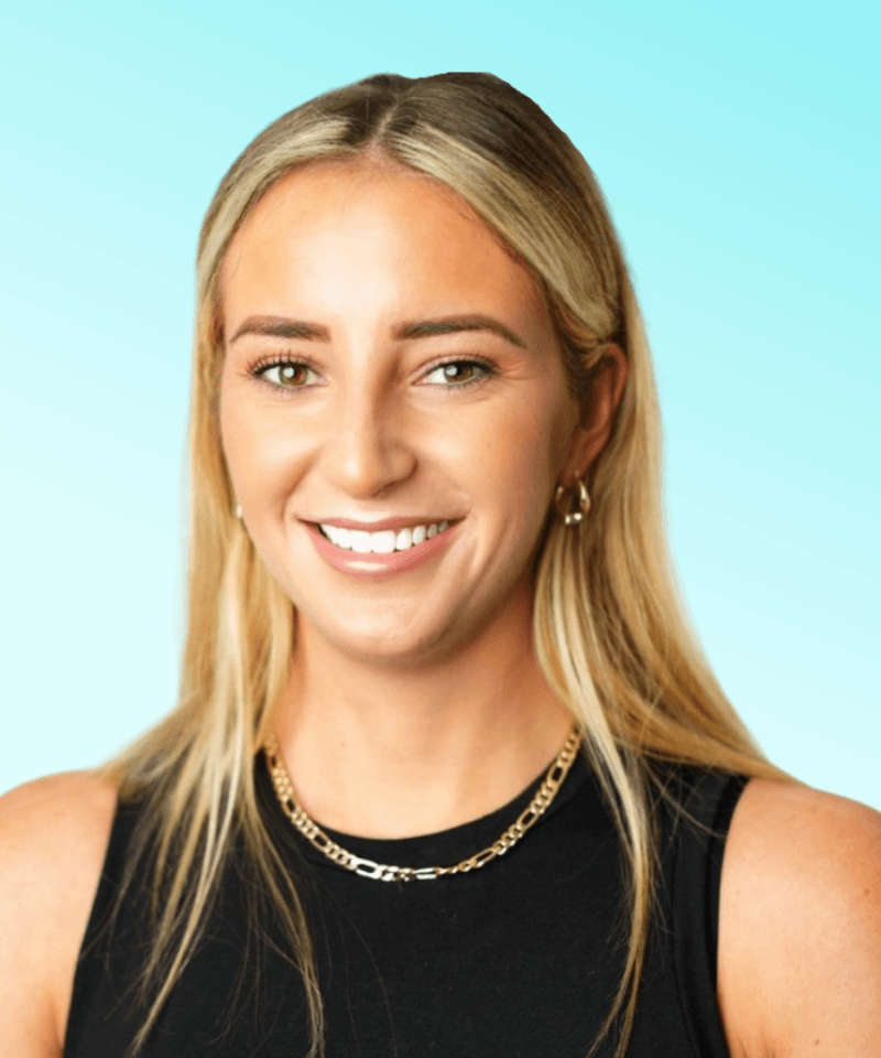 Woman smiling with black top and gold necklace in front of blue background