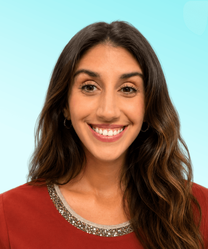 Woman with dark hair smiling in front of blue background