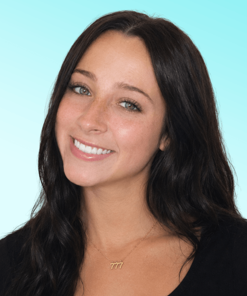 Woman with dark hair and black top smiling in front of blue background