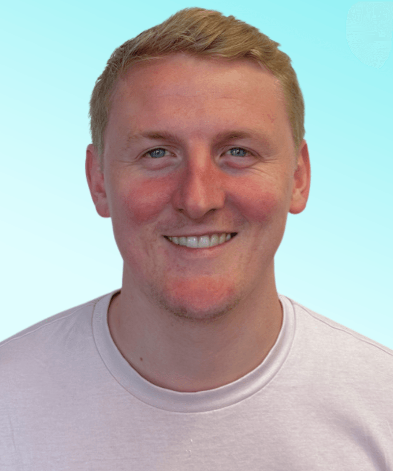 Man smiling with strawberry blonde hair in front of blue background