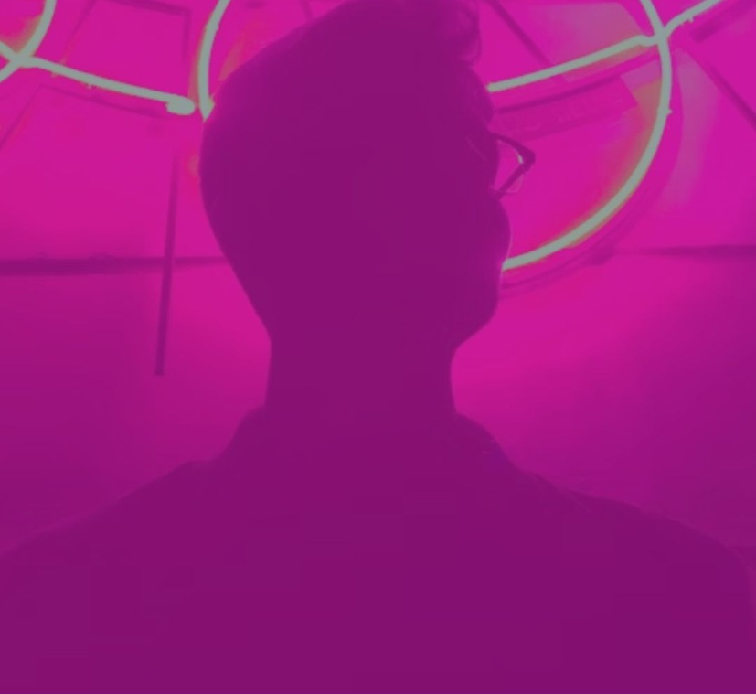Male silhouette beneath neon circular lights, representing innovation, creativity, and the intersection of technology and design.