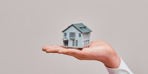 A person holding a house in the palm of their hands